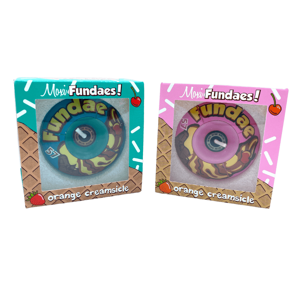 Two vibrant packages, each containing a Moxi Fundae skateboard wheel, stand side by side—the left one in turquoise and the right in pink—both proudly displaying the Orange Creamsicle label. Adorned with playful designs and ice cream cone motifs, these packages add a touch of fun to your ride. Pair them with our Sunshine Rollers Moxi Sk8 Candle (Grind Wax) for an effortlessly smooth cruising experience.